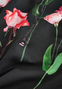 Donkere stof met levendige roze rozen en groene bladeren, met de tekst "by Ted Baker" subtiel weergegeven.