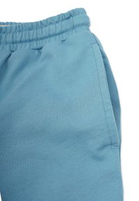 Ljusblå sweatpants med elastisk midja och sidoficka, tillverkade av mjuk bomull, med en slät textur och enkel design.