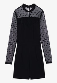 Combinaison noire avec de longues manches transparentes à pois, présentant un col haut, un devant plissé et une fermeture éclair au dos. Tissu doux avec des accents texturés.