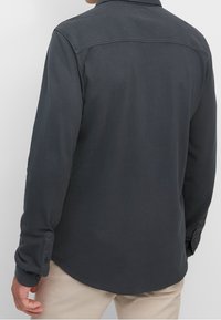 Dunkelgraues Langarmshirt mit Kragen, Knopfabnähten und glatter Textur. Verfügt über einen abgerundeten Saum und dezente Nähte auf der Rückseite.