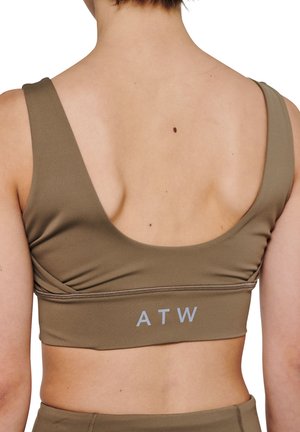 Brun sports-bh med brede stropper, lav ryg og en kant med "ATW" i lys grå. Glat tekstur med minimale sømme og et tætsiddende design.