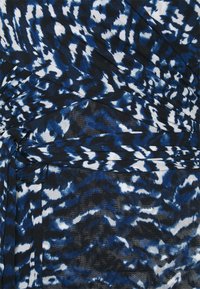 Klänning med ett blått och vitt abstrakt mönster, tillverkad av mjukt tyg med rynkig design och knyt-detalj vid midjan för extra textur.