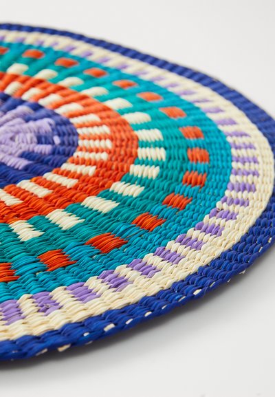 Tapis rond tissé présentant des couleurs vives : turquoise, orange, violet et crème. Design texturé avec des motifs concentriques et un bord bleu foncé.