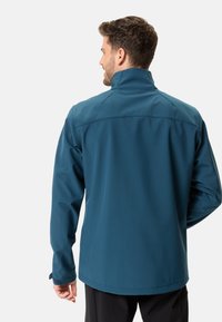 Veste softshell teal avec col haut et manches longues. Caractéristiques : coutures piquées et poignets ajustables. Design simple et fonctionnel.