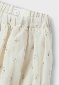 Pantaloni in tessuto leggero con vita elastica, caratterizzati da una stampa floreale pastello in rosa e verde su uno sfondo crema.