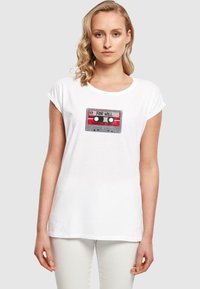 Valkoinen puuvillapaita, jossa on nauhakaappi grafiikka punaisilla yksityiskohdilla, tekstillä "FOR WILL" ja "STRANGER THINGS" -brändäys. Lyhyet hihat.