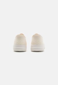 Lekki sneakersy z teksturowanym, miękkim beżowym siateczkowym wierzchem, podkreślonym białą gumową podeszwą i delikatnymi wzorami na pięcie.