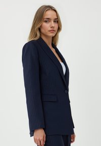 Marynarski blazer w paski z dopasowanym krojem, z zapięciem na jeden guzik, klapami i kieszeniami bocznymi, wykonany z gładkiego materiału.