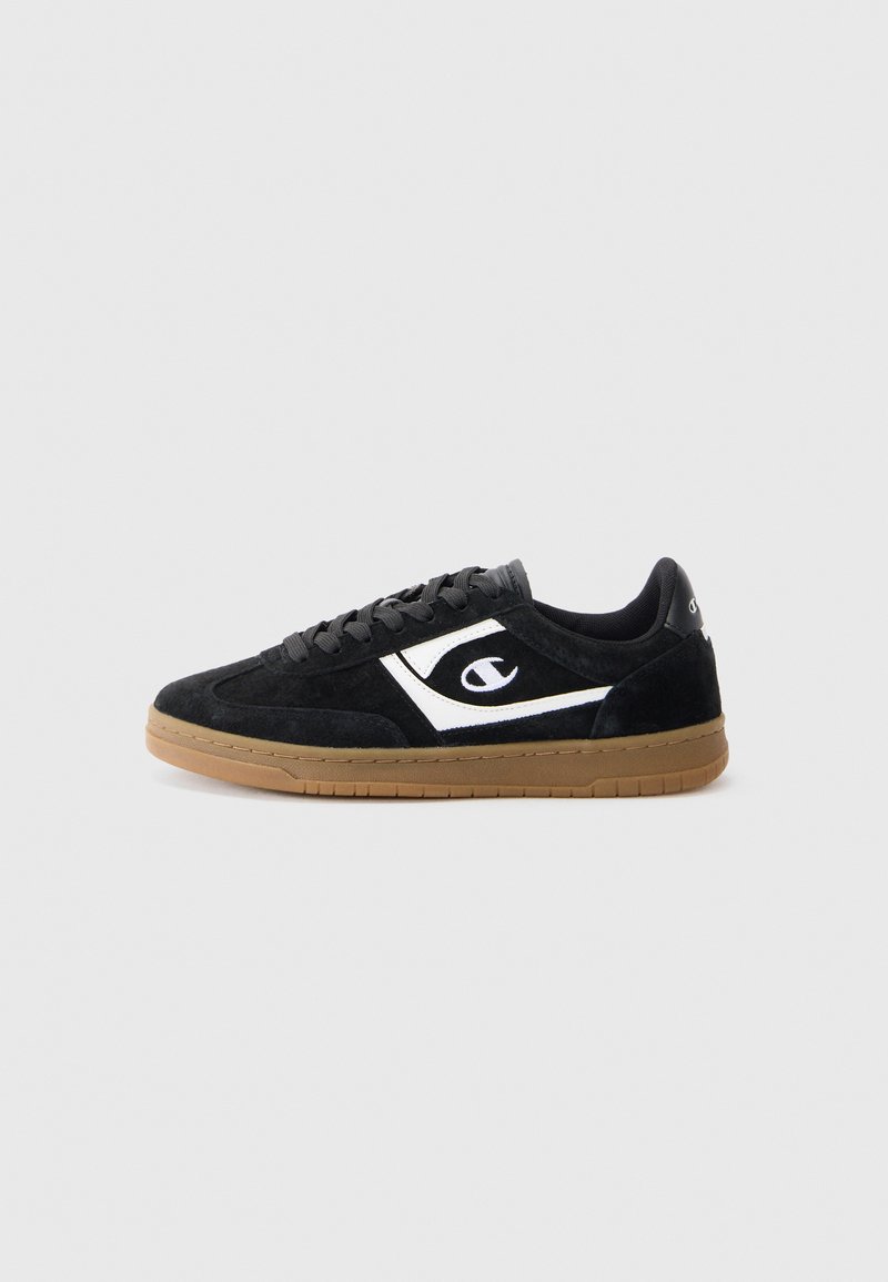 Black suede sneaker with a white logo, rubber gum sole, and black laces. Features a low-top design and smooth texture.