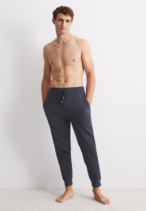 Donkergrijze joggingbroek met elastische tailleband en trekkoord. Strak ontwerp met boorden bij de enkels en een klein logo. Katoenmengsel.