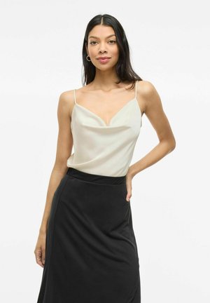 Lichtbeige satijnen camisole met een V-hals en dunne schouderbandjes, gecombineerd met een zwarte rok met een gladde textuur en subtiele draping.