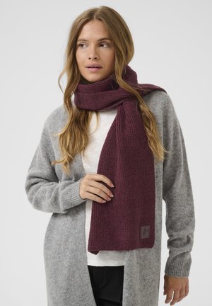 Écharpe en tricot bordeaux avec un motif texturé, fabriquée à partir d'un matériau doux, drapée autour du cou contre un cardigan gris.