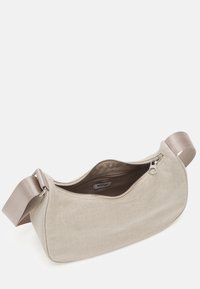 Sac à main en tissu beige avec une large sangle réglable et une fermeture éclair ouverte montrant le compartiment intérieur étiqueté "WEEKDAY".