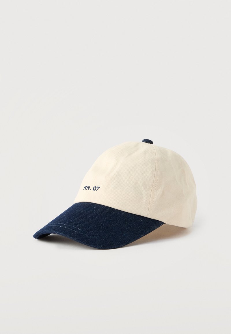 Casquette de baseball avec une couronne en coton crème et une visière en denim bleu foncé, ornée du texte brodé "NN. 07" à l'avant.