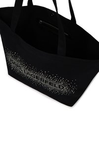 Juodas kanvas pirkinių maišas su sidabriniu taškiniu raštu vienoje pusėje, su dviem tvirtais rankenoms ir užtrauktuku uždaroma kišene viduje.