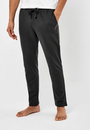 Zwarte joggingsbroek van zacht materiaal, met een elastische tailleband met drawstring en zijzakken, en een klein contrasterend logo.