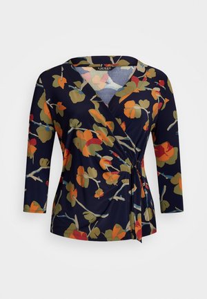 Blouse portefeuille bleu marine avec motif floral aux couleurs automnales en orange, rouge, vert et beige, manches trois-quarts et détail noué sur le côté.