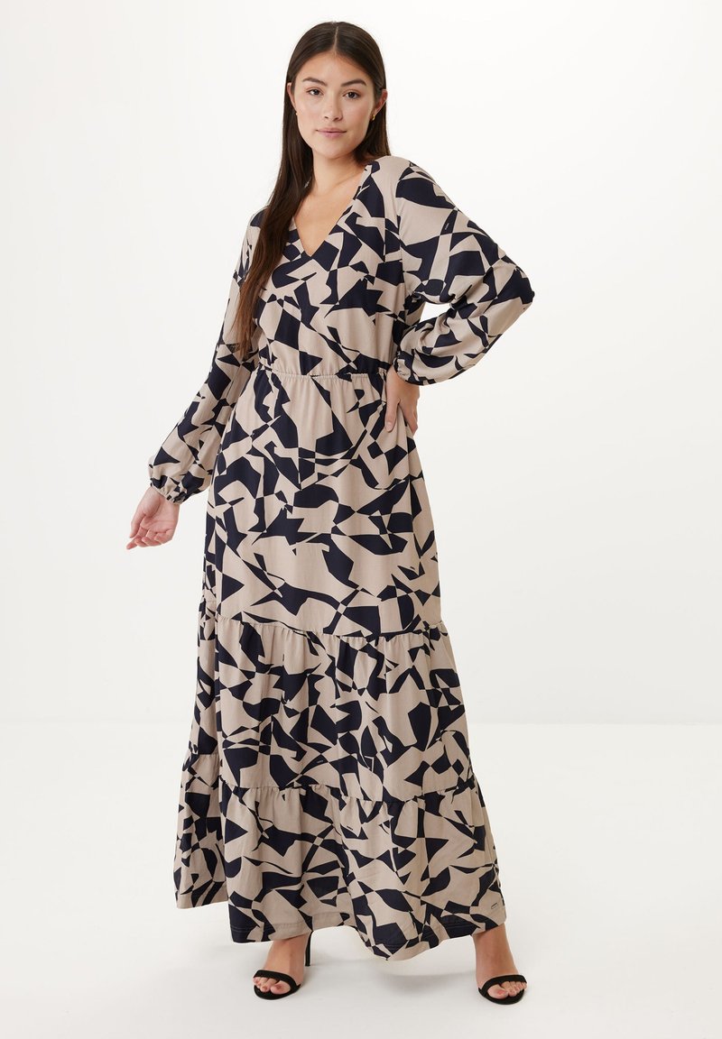 Maxi šaty z béžové látky s abstraktním námořnickým vzorem, výstřih do V, dlouhými rukávy, vrstveným designem a nařaseným pasem. Černé otevřené lodičky.