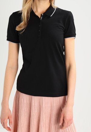 Czarna koszulka polo z krótkim rękawem, o dopasowanym kroju, z pięcioma guzikami i kontrastową lamówką na kołnierzu. Połączona z plisowaną różową spódnicą.