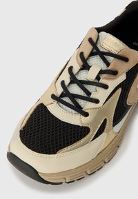 Shoe with a black mesh upper, cream and tan leather accents, and black laces; features a slightly textured beige rubber sole.