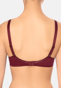 Vista posteriore di una persona che indossa un reggiseno rosso scuro con spalline regolabili e chiusura a gancio su uno sfondo chiaro.