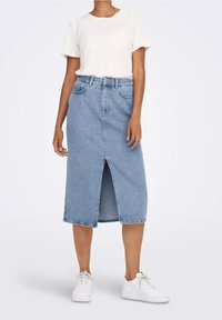 Sukně z džínoviny v světlé modré barvě s přímým střihem, předním rozparkem a pěti kapsami. Kombinováno s bílým tričkem s krátkými rukávy a bílými teniskami.