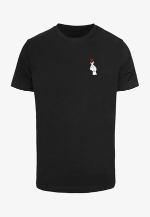 Czarny T-shirt z małą białą dłonią wykonującą gest serca palcami i malutkim czerwonym serduszkiem nad palcami na górnej części klatki piersiowej.