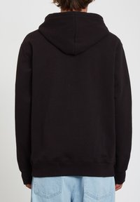 Felpa nera con cappuccio dal tatto morbido, con tasca a marsupio, polsini e orlo a costine. La vista dal retro rivela un design semplice.