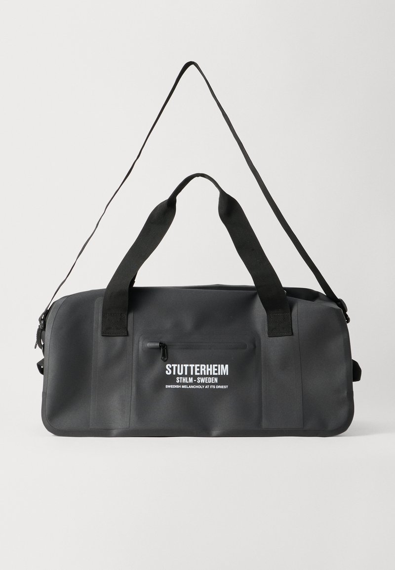 Borsa a tracolla nera impermeabile con doppi manici superiori, tracolla regolabile, tasca frontale con zip e dettagli del logo bianco. Texture liscia.