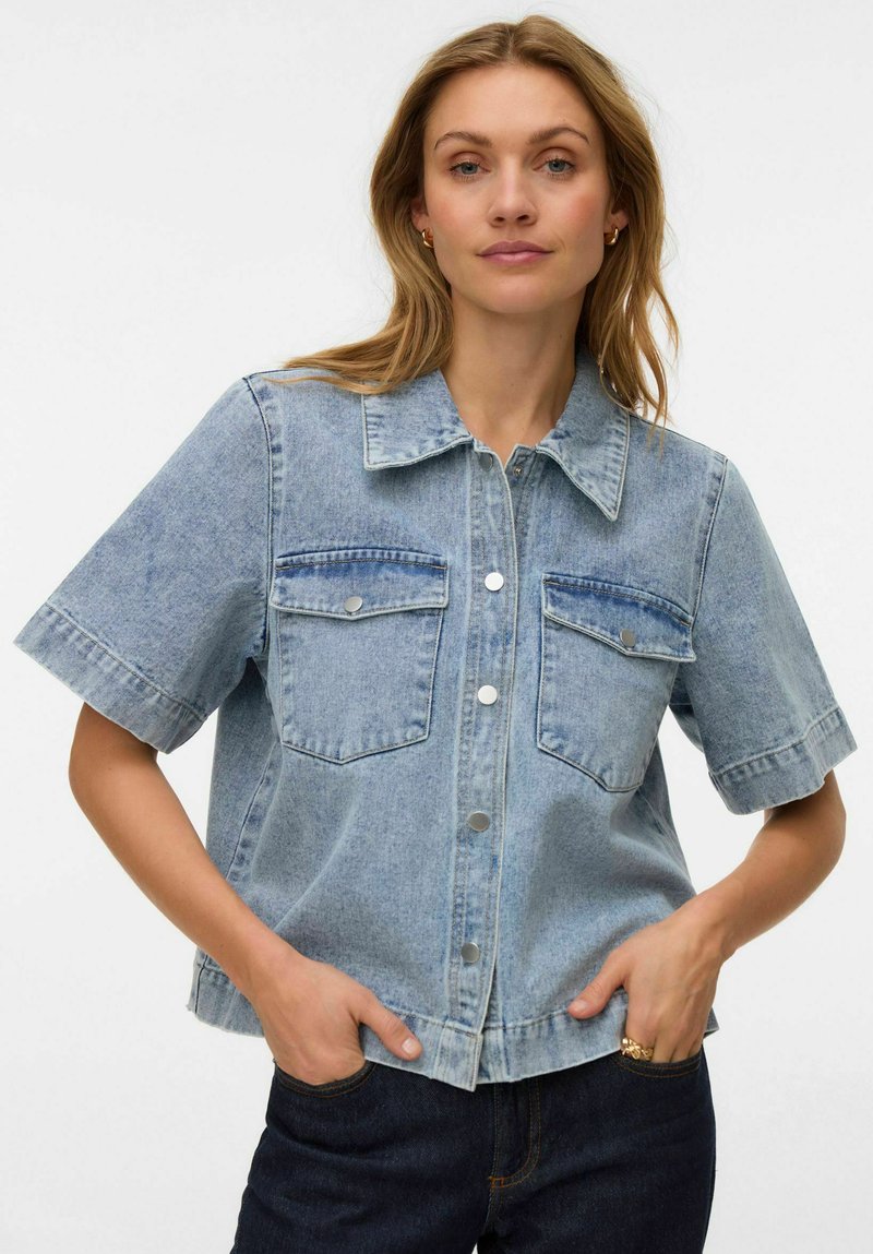 Lyseblå denim jakke med korte ermer, knappelukking foran, to brystlommer og krage. Casual, avslappet passform med frynsete kant.