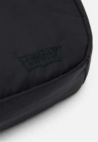 Levi's® MEDIUM BANANA SLING  EMBROIDERED BATWING UNISEX - Ľadvinka - regular black