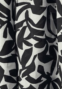 Tissu noir et blanc présentant de grands motifs de feuilles abstraits audacieux. Texture douce avec une finition lisse et un léger éclat.