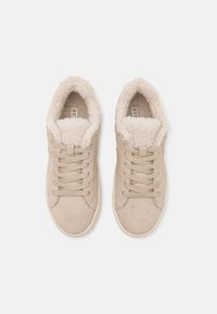 Baskets beige en daim à lacets avec une épaisse doublure en polaire blanche et moelleuse, vues de dessus sur fond blanc.