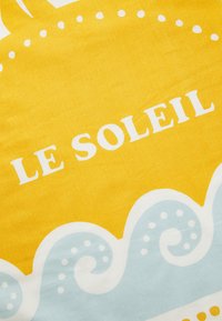 Žltá látka s bielym textom "LE SOLEIL", s bledomodrými vlnitými vzormi pozdĺž spodnej časti, textúrovaný povrch a živé farby.