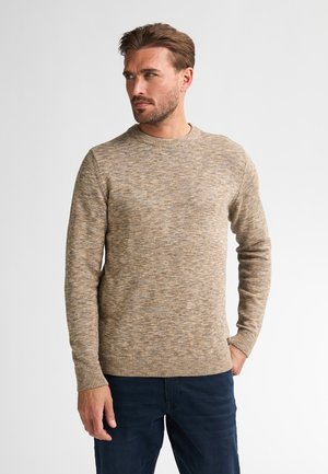 Lichtbruine gebreide trui met een textuur van gemarmerd patroon, ronde halslijn en geribde manchetten en zoom, gecombineerd met donkerblauwe broek.