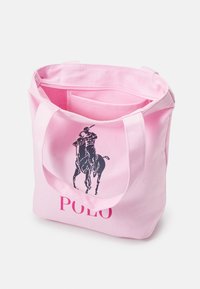 Bolso de mano de algodón rosa con gráfico de jugador de polo negro y texto "POLO". Presenta asas resistentes y un interior espacioso.