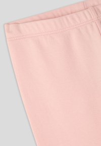Pantaloni rosa chiaro con una texture morbida e liscia e elastico in vita, caratterizzati da cuciture ben rifinite.