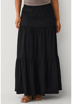 Sort lagdelt maxinederdel båret med beige åbne hæle, med elastisk taljebånd og tekstureret stof.