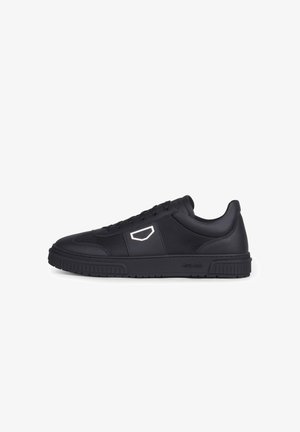 Zapatilla deportiva negra de corte bajo con cordones delanteros, paneles laterales texturizados, un logo geométrico blanco y una suela gruesa de goma.