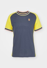 Sportovní tričko s krátkým rukávem, tmavě modré barvy s jasně žlutými síťovanými bočními panely, s červenými a bílými pruhovanými lemovkami kolem výstřihu a rukávů.