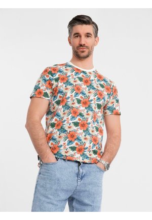 Bloemended t-shirt met oranje en witte hibiscus bloemen en groene bladeren op een crèmekleurige achtergrond. Korte mouwen en een ronde halslijn.