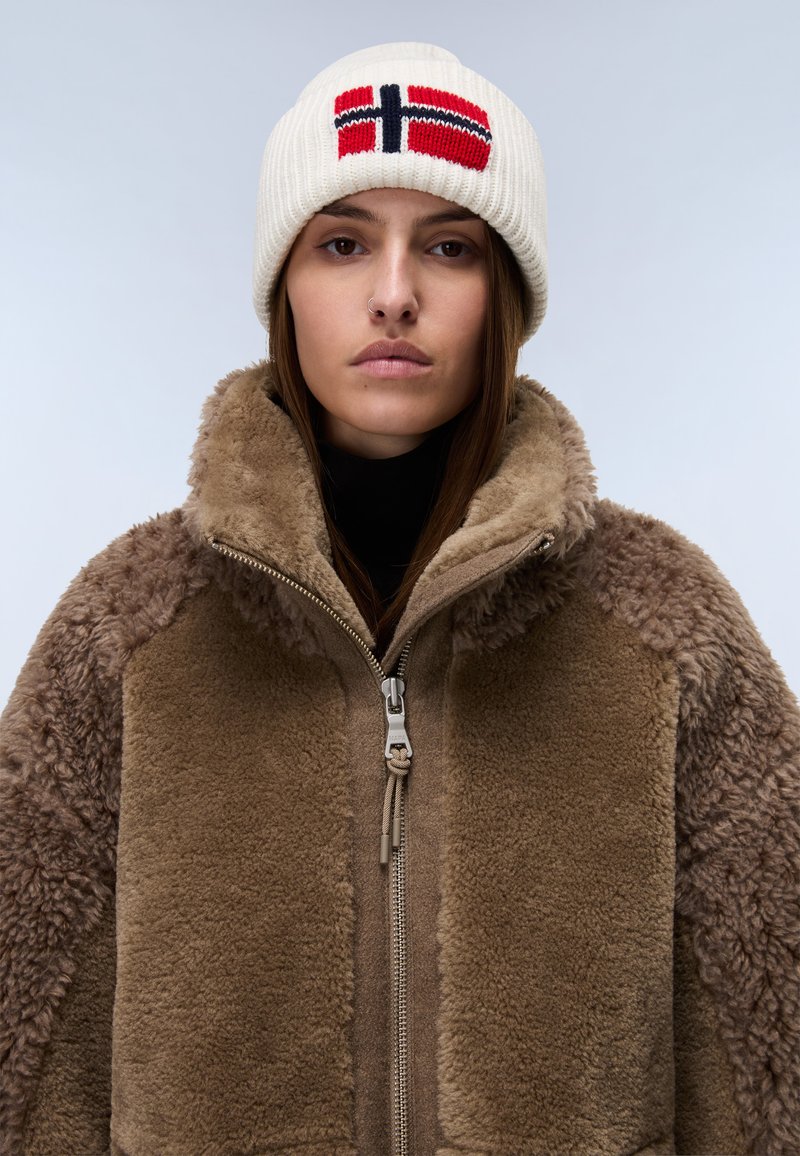 Chaqueta de forro polar marrón con tejido texturizado, cuello alto y detalles con cremallera. Gorro de punto blanco con diseño de la bandera noruega en rojo y azul.