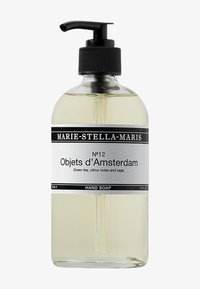 Bottiglia di vetro trasparente con pompette nera. L'etichetta presenta testo in bianco e nero. Contiene sapone liquido giallo chiaro con note di tè verde e salvia.