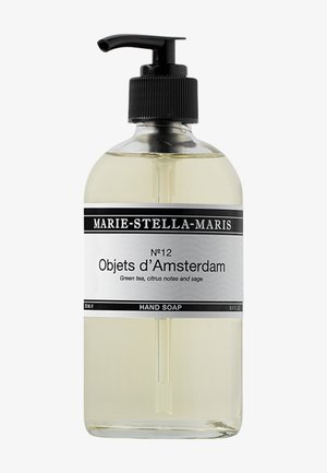 Bouteille en verre transparent avec un bouchon-pompe noir. L'étiquette présente du texte en noir et blanc. Contient un savon liquide jaune clair aux notes de thé vert et de sauge.