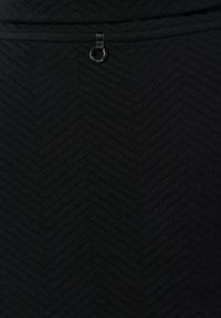 Tessuto nero con un motivo a spina di pesce, dotato di un piccolo anello nella parte superiore, realizzato in materiale testurizzato.