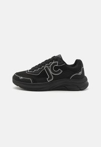 Zapatillas deportivas negras con materiales de malla y cuero, que presentan un atrevido logo "JC", costuras grises contrastantes y una suela gruesa texturizada.