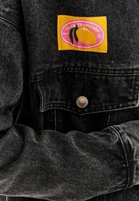 Czarna kurtka dżinsowa z żółtą i różową naszywką "CLUB TROPICANA" z motywem mango. Metalowe zapięcie na zatrzask i białe detale haftu.