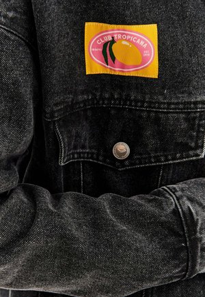 Černá denimová bunda s žlutou a růžovou nášivkou "CLUB TROPICANA" s designem manga. Kovové zapínání na cvoky a bílé švy.