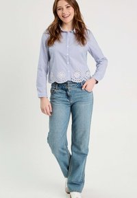 Chemise à rayures bleu et blanche avec un ourlet festonné en œillets, associée à un jean droit délavé et des baskets blanches.
