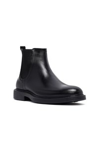 Stivale alla caviglia in pelle nera con pannello laterale elastico, linguetta sul retro, punta rotonda e tacco basso impilato su sfondo bianco.